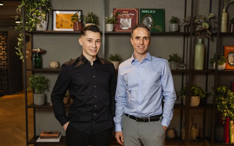 Julian und Michael Odermatt stehen nebeneinander vor einem Bücherregal im Büro.